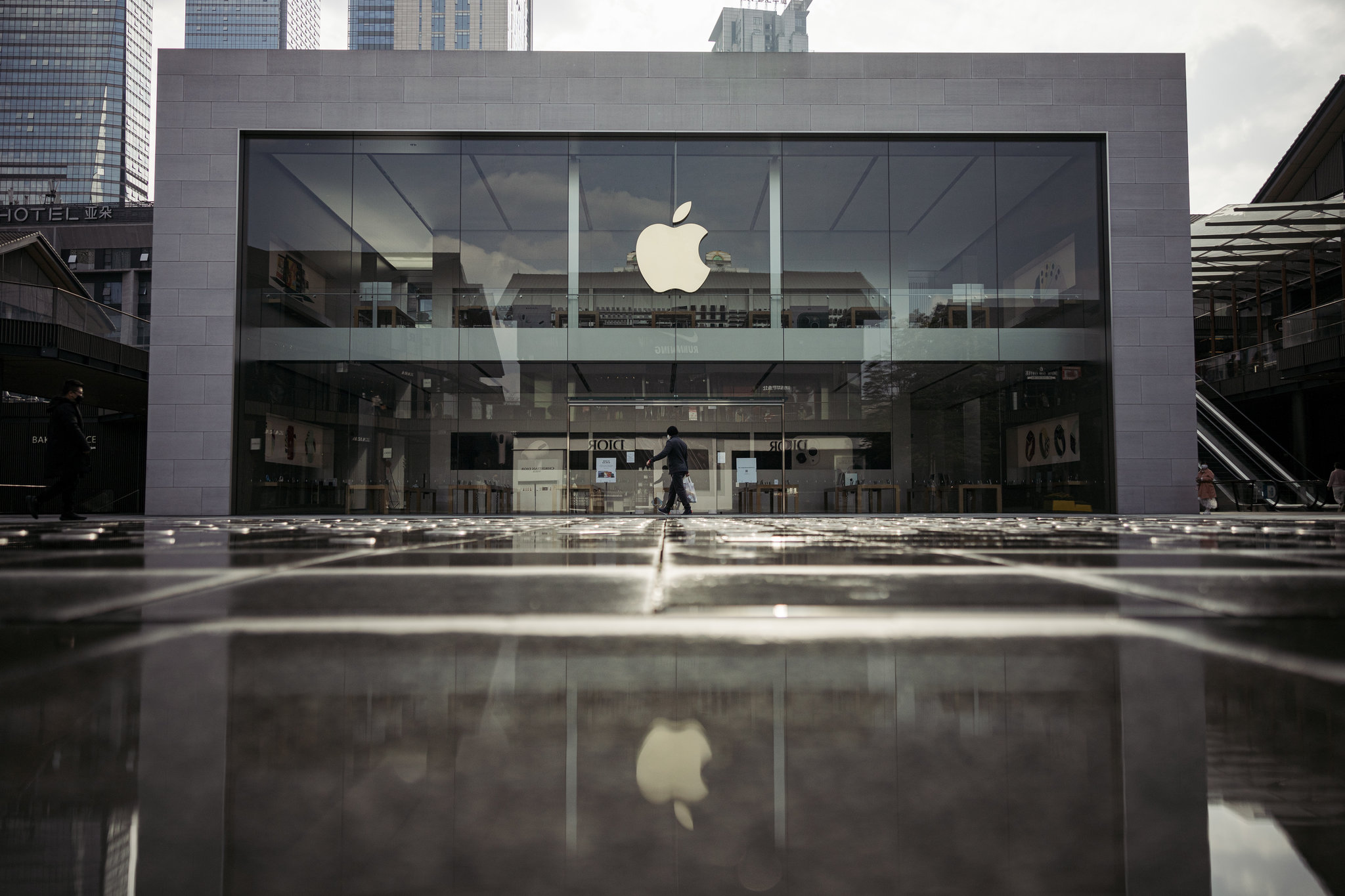 A person walking in front of an apple store.