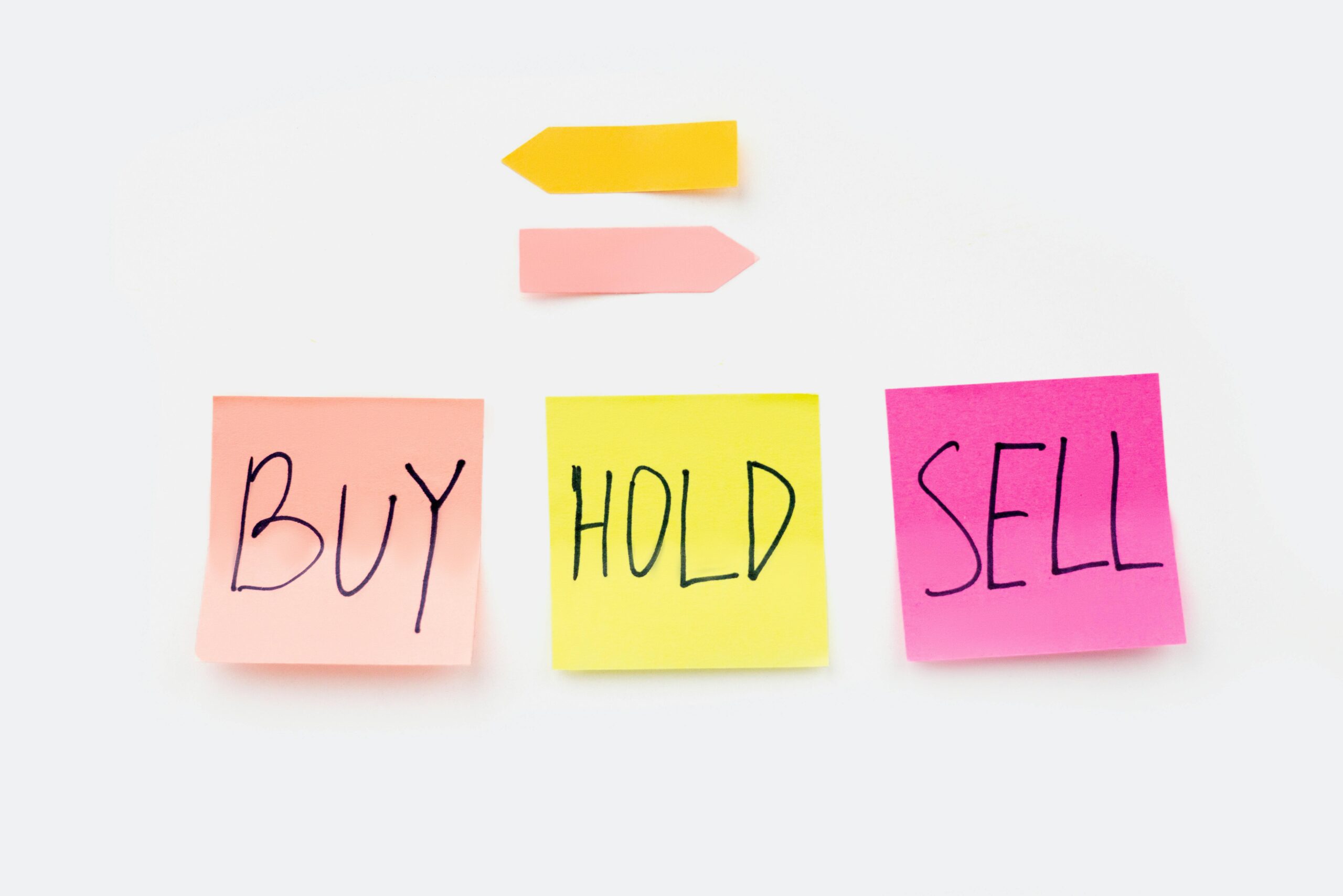 Colorful sticky notes with financial terms 'Buy', 'Hold', and 'Sell' on a clean white backdrop.