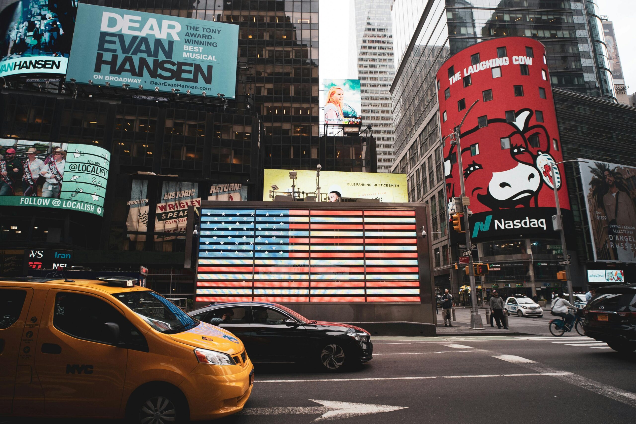 Dynamic view of Times Square with iconic billboards and yellow taxi in New York City.