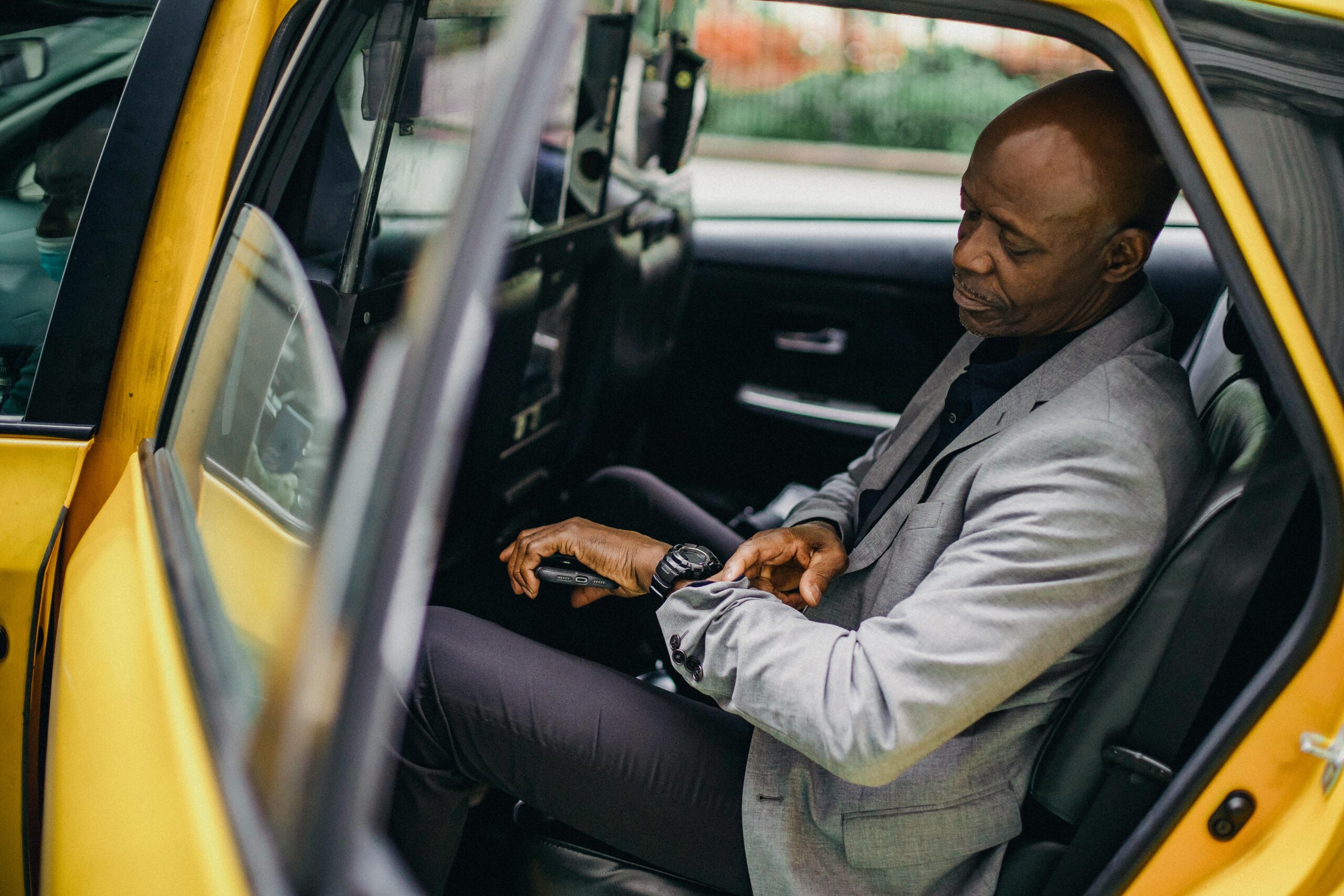 A well-dressed man checks his watch in a parked taxi, conveying punctuality and focus.