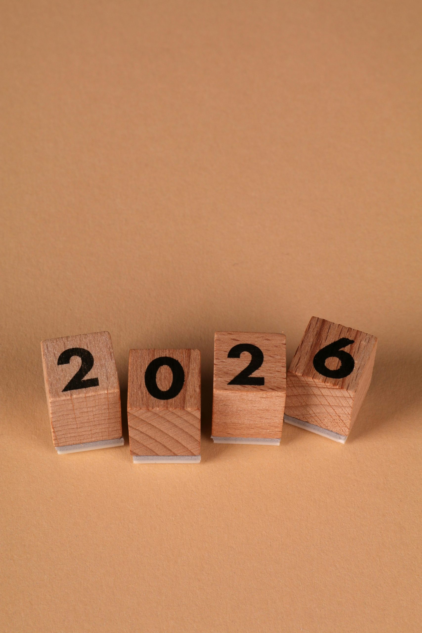 Wooden blocks forming the year 2026 on a warm beige background, symbolizing the new year.