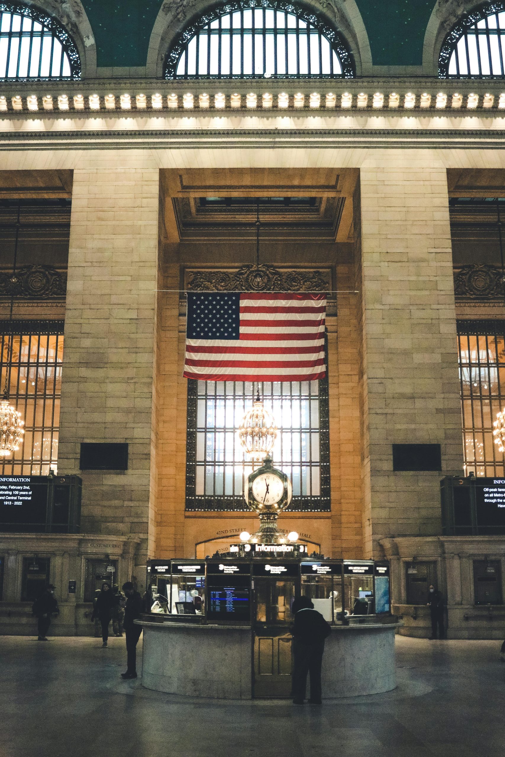 Inside view of Grand Central Terminal with American flag prominently displayed, showcasing iconic architecture.